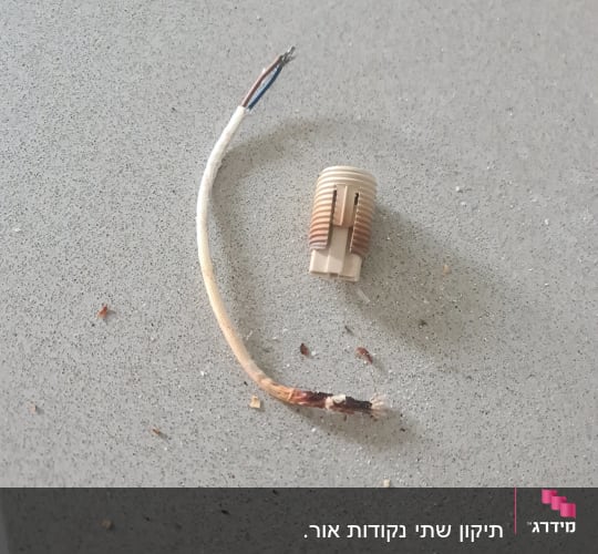 חוט חשמל חשוף ומחבר פלסטיק על משטח אפור